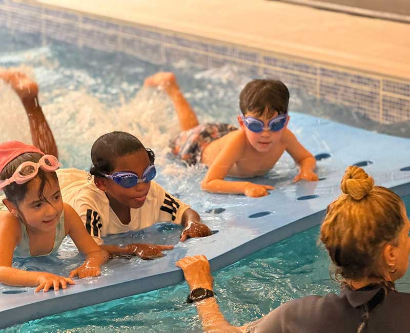שיעור שחייה לילדים עם מדריכה ותרגול על מתקן ציפה במים