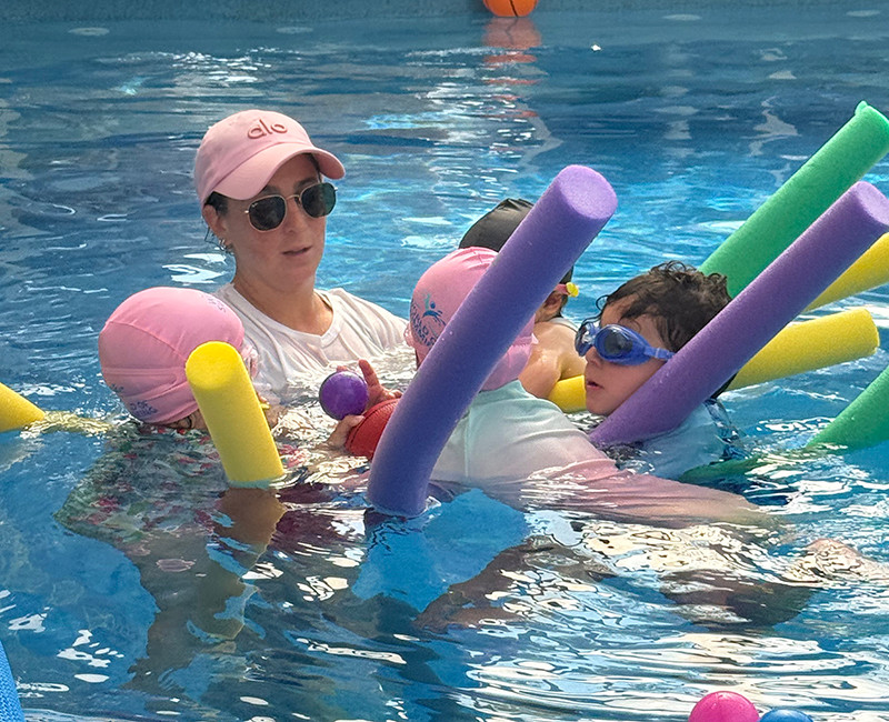שיעור שחיית תינוקות עם מדריכה ותינוקות במים בעזרת מצופים צבעוניים