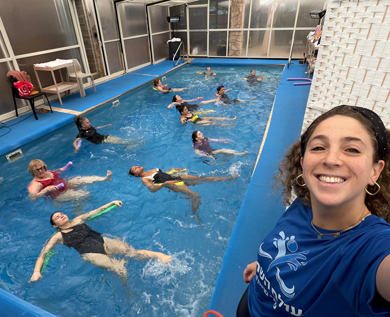 שיעור אירובי מים קבוצתי עם מדריכה וקבוצת נשים מתאמנות בבריכה