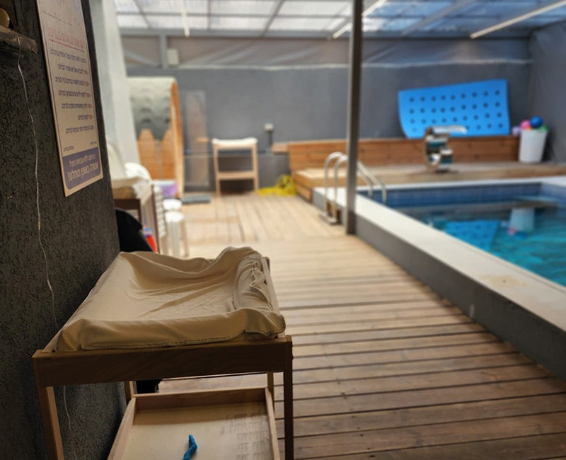 מגבות מסודרות במתחם בריכה לצד אזור ישיבה ובריכה מקורה נקייה ומטופחת