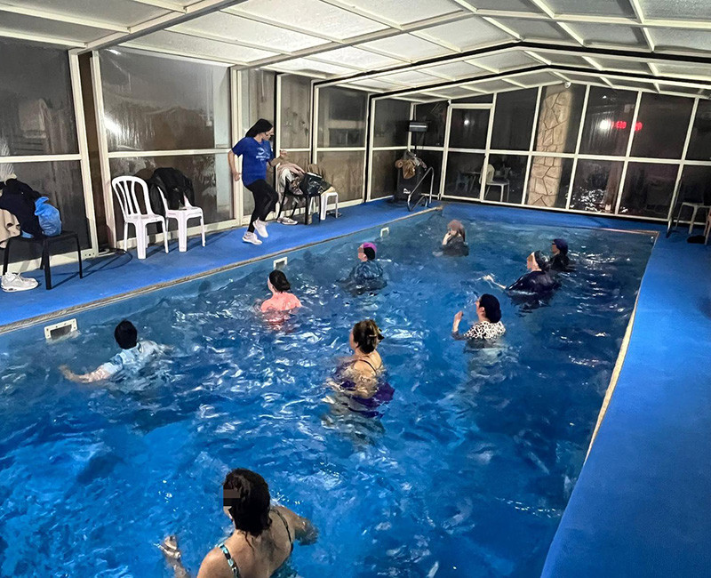 שיעור אירובי מים לנשים בבריכה עם מדריכה וקבוצה בתרגול משותף